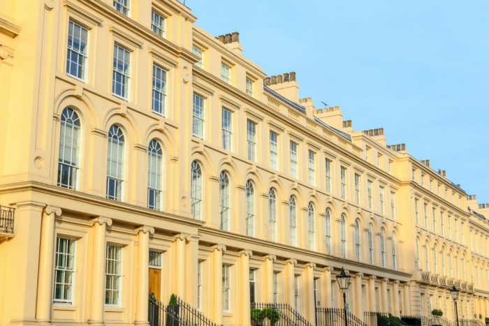 Row of cream-coloured Regency townhouses with tall sash windows and ionic columns on a London terrace