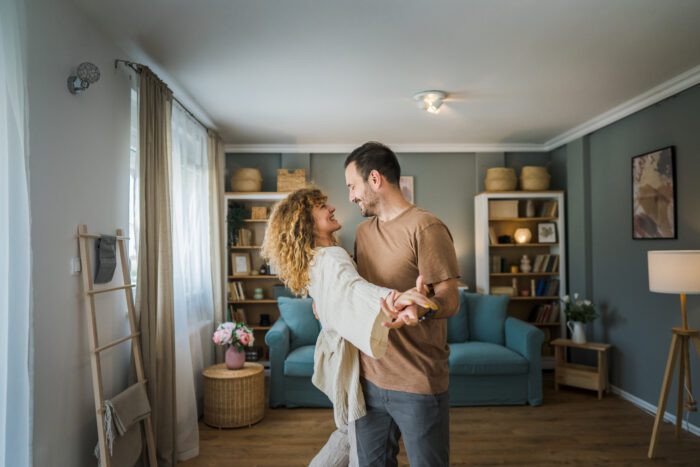 happy cohabiting couple dancing in living room