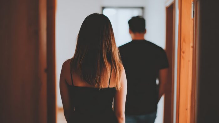 A woman walks away from a man in a softly lit hallway, illustrating a dramatic moment of emotional separation. Cinematic backlighting highlights the scene’s tension and storytelling depth.